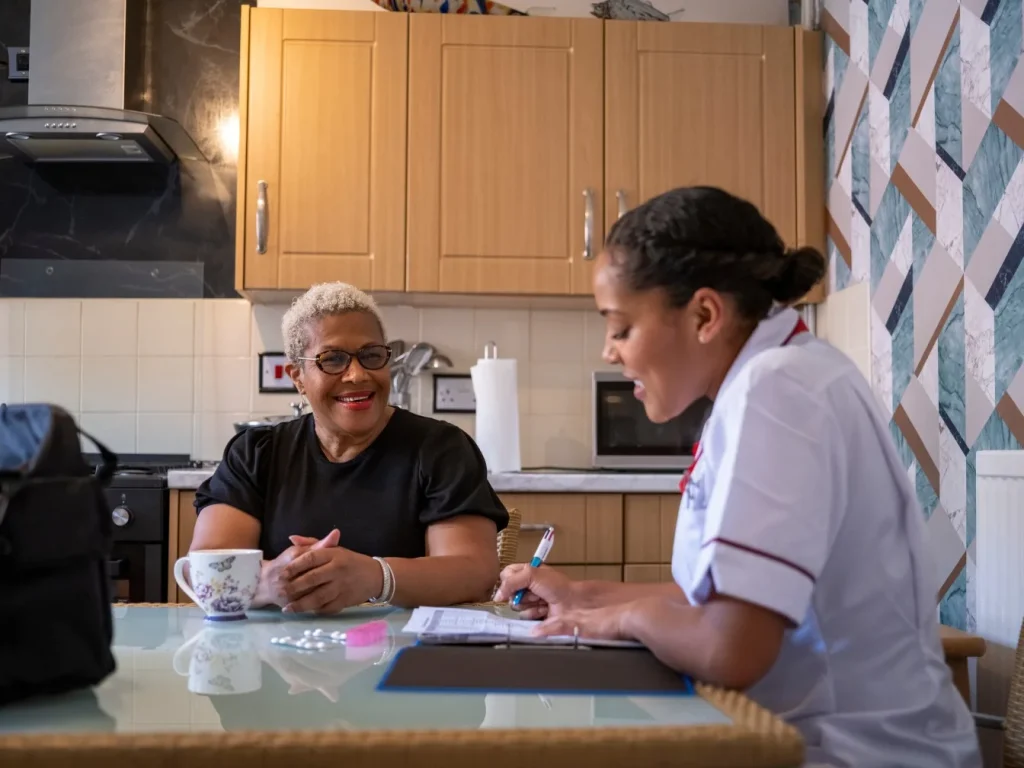 Nurse visiting patient at home, sitting at kitchen table together