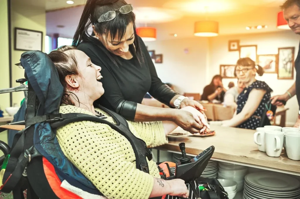 Disabled woman in wheelchair holding hands with carer